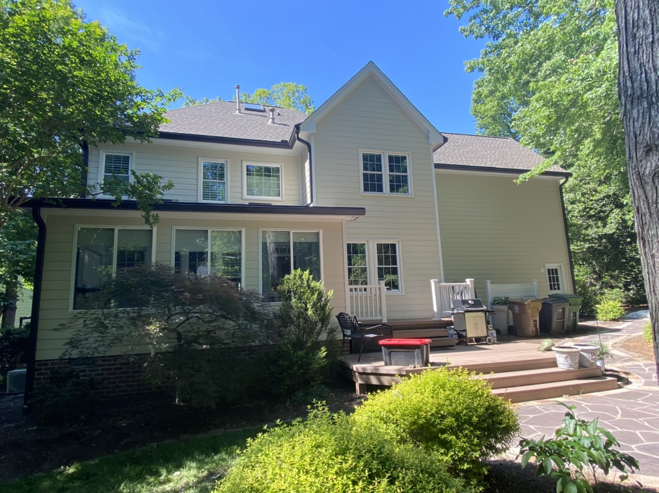 A beige two-story home with white Carolina siding and windows, set in a sunny backyard in Raleigh or Apex, NC.