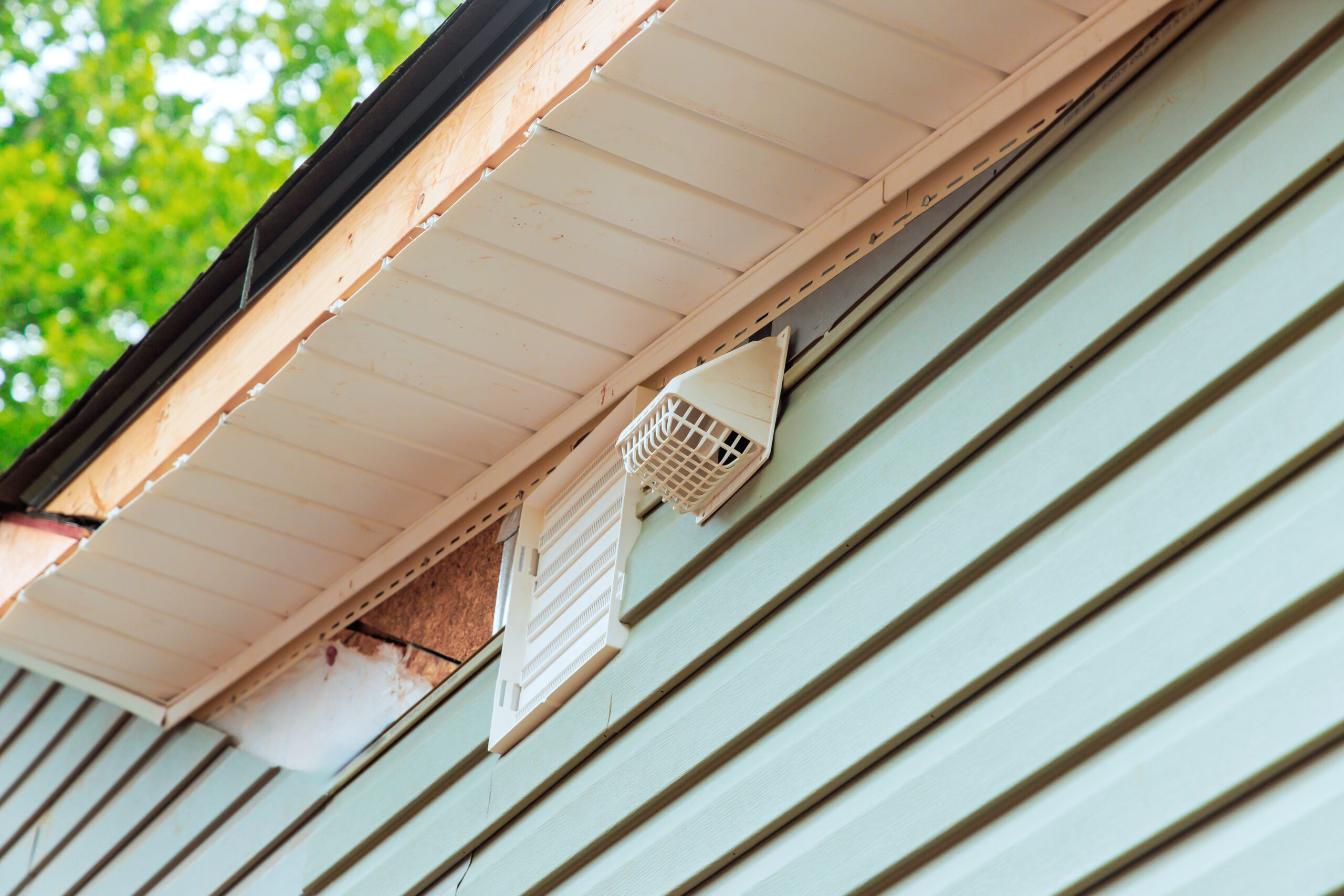 Ventilation system shown mounted on light colored exterior wall of house during construction new home