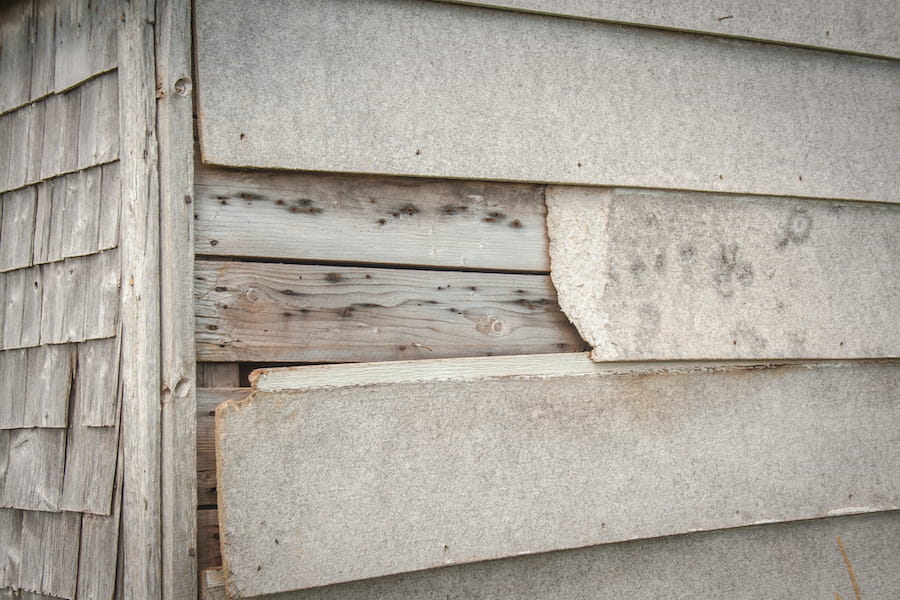 Worn Wooden Wall with Peeling Gray Paint
