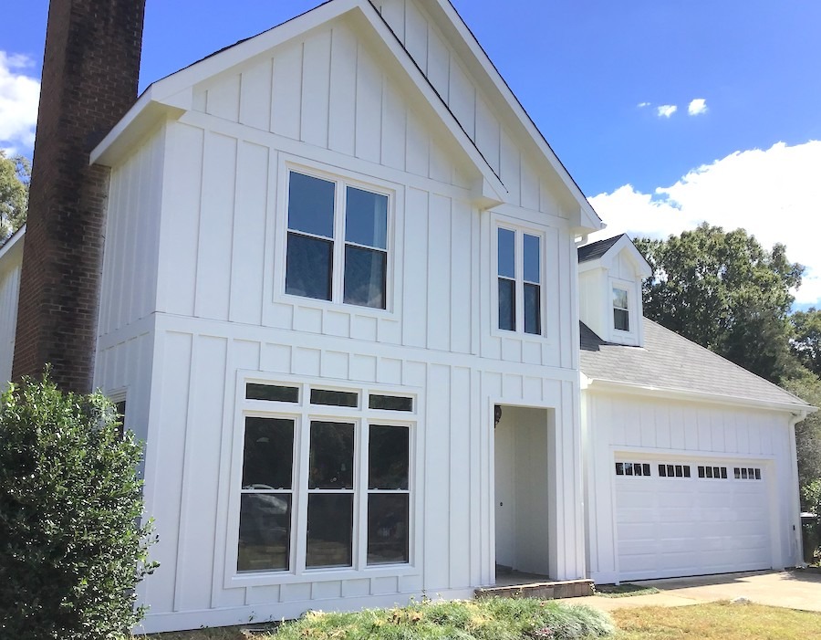 A white two-story house with board and batten siding and large windows, ideal for Raleigh & Apex, NC siding or window upgrades.